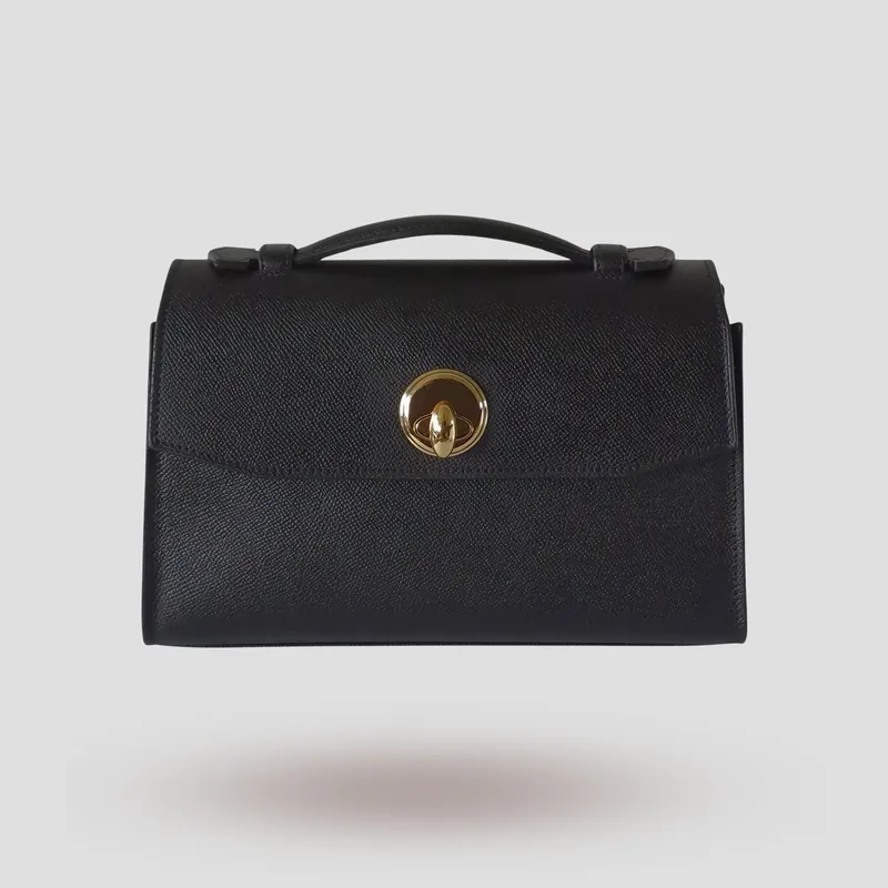 A custom compact, architectural flap bag handcrafted in black premium Epsom cowhide leather with a deep red lambskin lining.