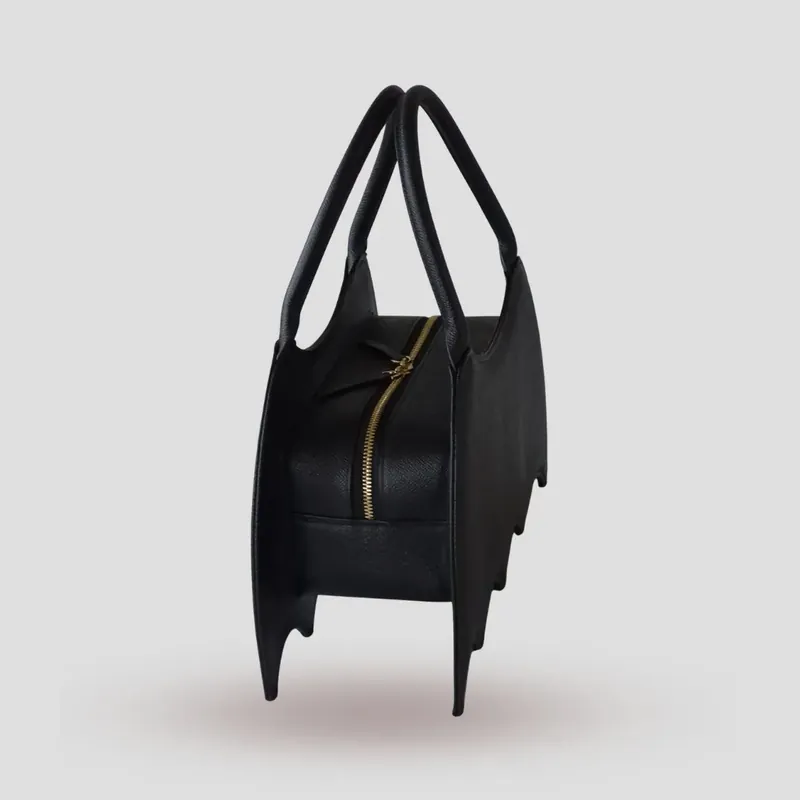 A custom bat-shaped handbag, handcrafted in black Epsom full-grain leather, with a grommet at the base of the handle for attaching charms.