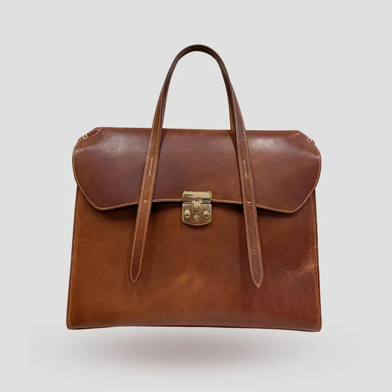A custom crossbody bag/briefcase handcrafted in cognac premium Horween oil pull-up leather.