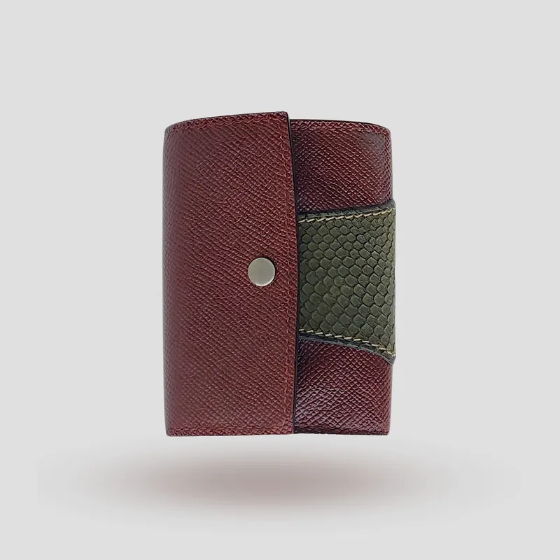 A custom wallet handcrafted in burgundy premium cowhide leather, featuring a bold, asymmetrical wrap accent in salmon leather, paired with a supple goatskin lining.