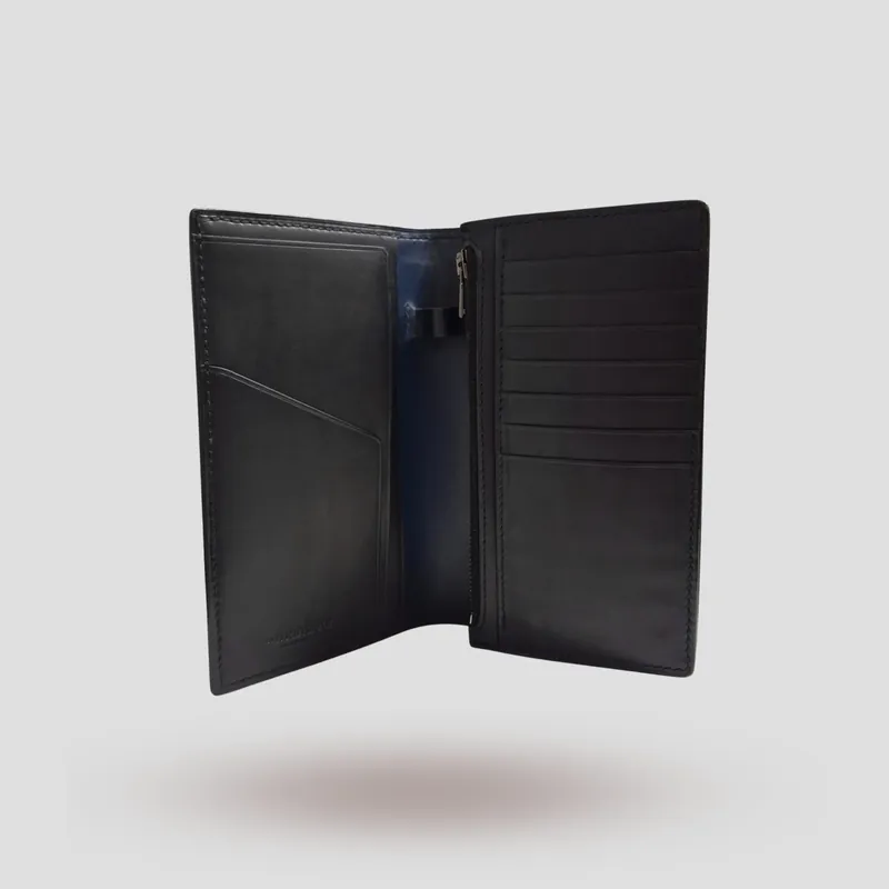 A custom long wallet handcrafted in black premium vegetable-tanned cowhide leather on the outside, and oiled Buttero navy blue vegetable-tanned cowhide leather inside.