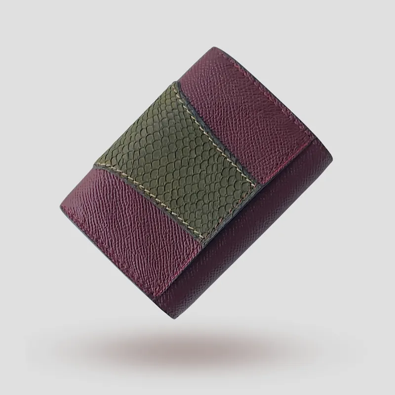 A custom wallet handcrafted in burgundy premium cowhide leather, featuring a bold, asymmetrical wrap accent in salmon leather, paired with a supple goatskin lining.
