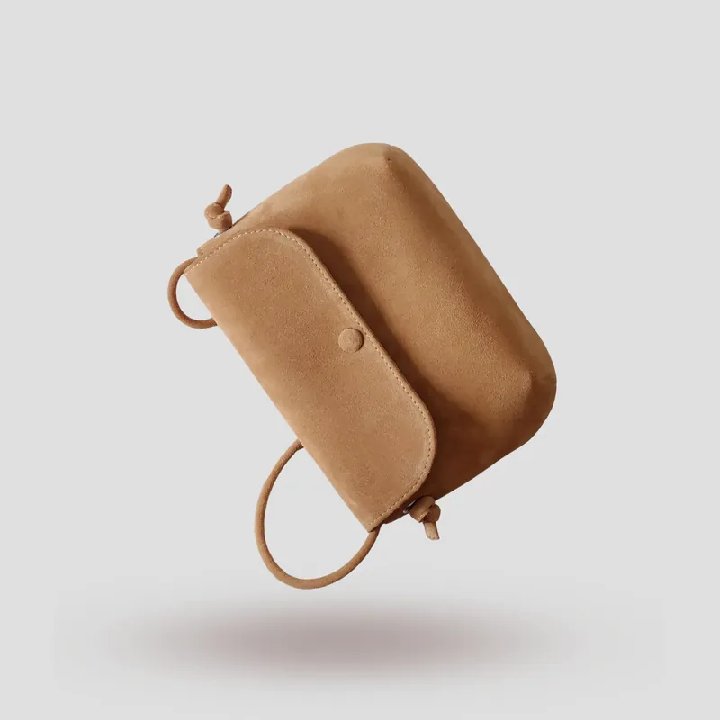 A signature crossbody bag handcrafted in beige premium suede.