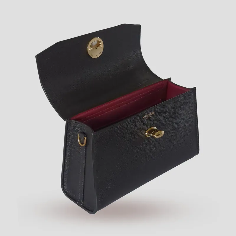 A custom compact, architectural flap bag handcrafted in black premium Epsom cowhide leather with a deep red lambskin lining.