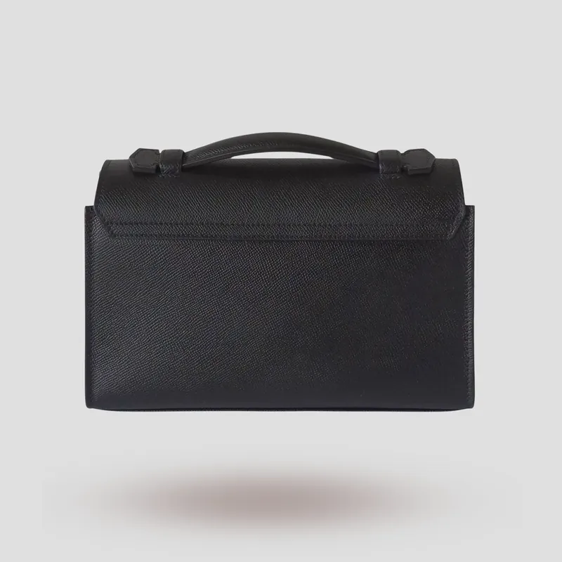 A custom compact, architectural flap bag handcrafted in black premium Epsom cowhide leather with a deep red lambskin lining.