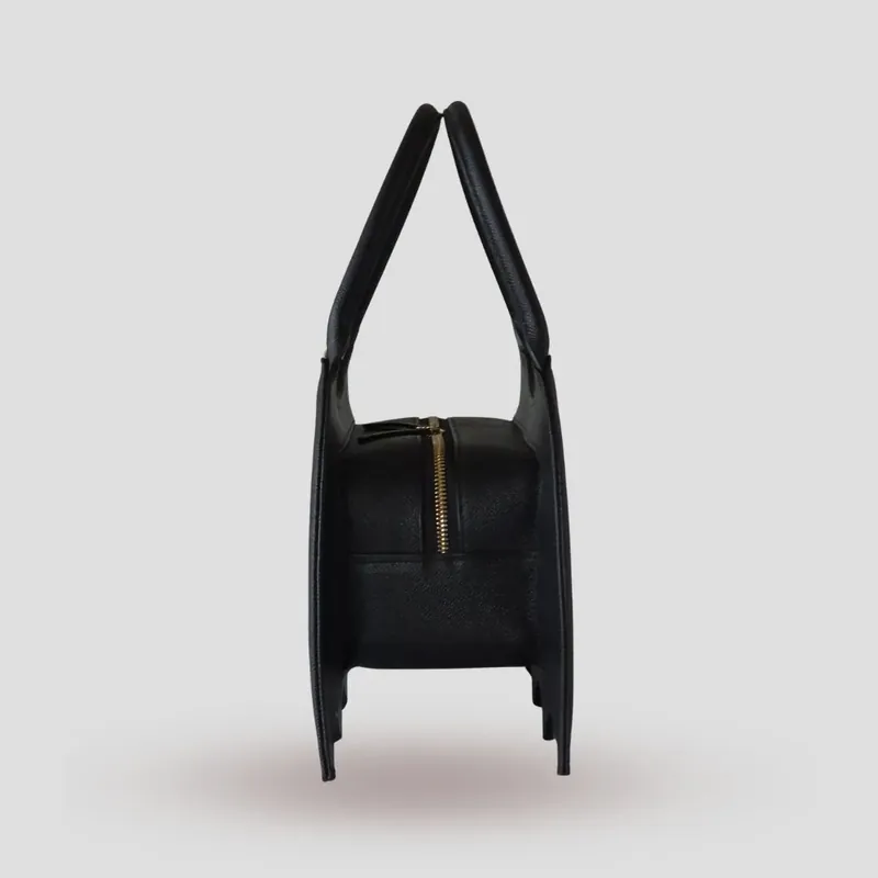 A custom bat-shaped handbag, handcrafted in black Epsom full-grain leather, with a grommet at the base of the handle for attaching charms.