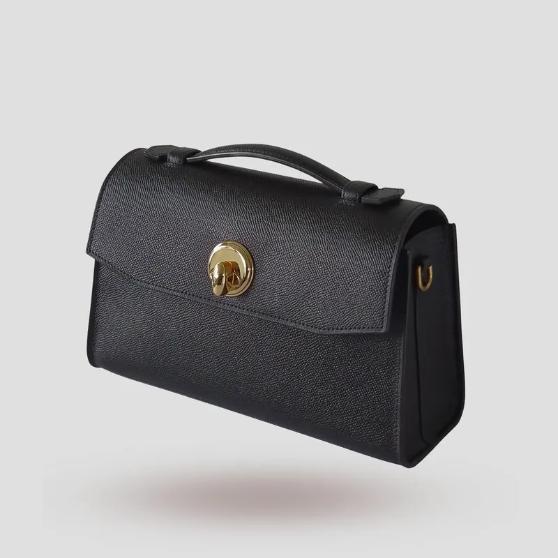 A custom compact, architectural flap bag handcrafted in black premium Epsom cowhide leather with a deep red lambskin lining.