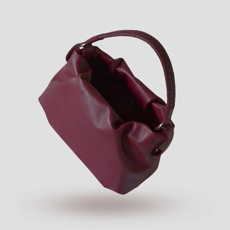 A custom soft mini bucket bag handcrafted in deep wine red full-grain aniline calfskin with a burgundy lambskin lining.